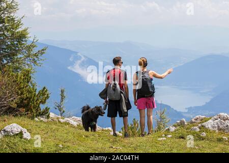 Scuotipaglia, giovane con cane guardando sopra la valle, Dobratsch parco naturale, Villacher Alpi / Villacher Alpe, Carinzia / Carinzia, Austria Foto Stock