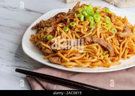 Mangiare carne bovina cinese lo mein tagliatelle con bacchette Foto Stock