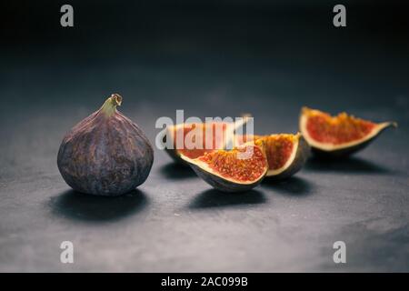 Fichi freschi, fotografia creativa, tagliere di legno, succosa fresche, sfondo scuro Foto Stock