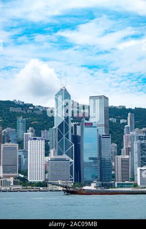 Vista dello skyline di Hong Kong. Una chiatta trasporta merci, sostenendo il commercio e l'economia della città. Foto Stock