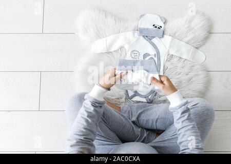 Aspetta la donna incinta toccando il suo ventre mentre guardando ecografie, seduto sul comodo letto con coperte, cuscini, canondigitalcamera. Foto Stock