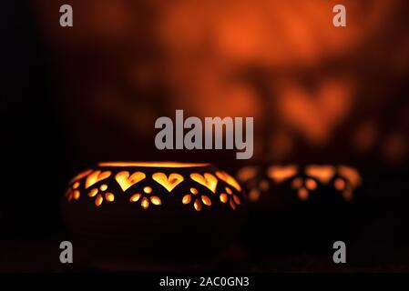 Ceramica decorativa lanterne con ritagli di cuore illuminato da candele incandescente Foto Stock