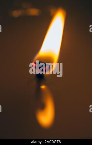 Extreme close-up della fiamma di una candela. La riflessione della fiamma nella candlewax fuso. Foto Stock