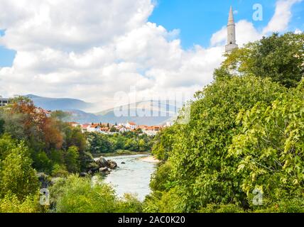 Il fiume Neretva fluisce dalle antiche mura che circondano la città vecchia sezione di Mostar, Bosnia Foto Stock