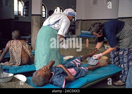 Volunteer bagna gamba di un paziente a Madre Teresa la casa dei moribondi di Calcutta, in India Foto Stock