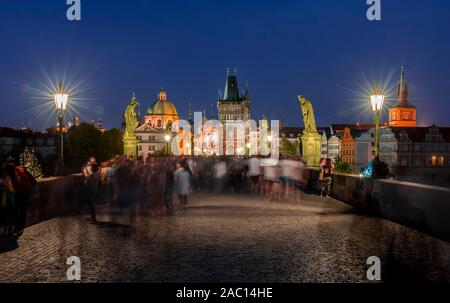 Karluv, la maggior parte delle persone sul Ponte Carlo al tramonto, nel retro cupola della chiesa Kreuzherrenkirche con torre del ponte della città vecchia di Praga, Boemia Foto Stock