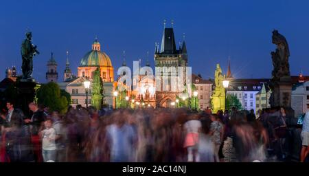 Karluv, la maggior parte delle persone sul Ponte Carlo al tramonto, nel retro cupola della chiesa Kreuzherrenkirche con torre del ponte della città vecchia di Praga, Boemia Foto Stock