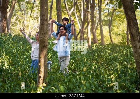 Felice asian madre padre e figlio a piedi nei boschi Foto Stock