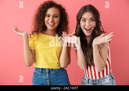 Immagine di piacere ragazze multinazionale chiedendo e alzando le mani nella sorpresa isolate su sfondo rosa Foto Stock