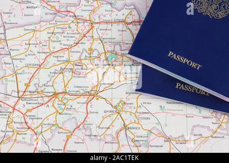 Pezzi di due passaporti blu close-up su un atlas Foto Stock