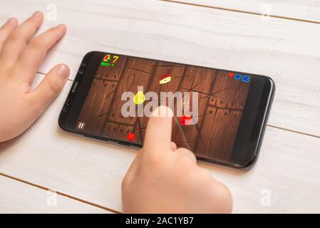 Sarajevo, Bosnia Erzegovina - 30 Novembre 2019: Kid playing Fruit Ninja video gioco su moderne smart phone close up Foto Stock