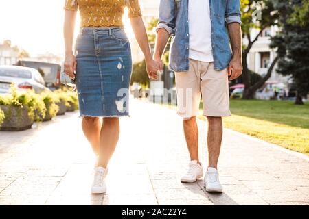 Immagine ritagliata di una coppia in amore di trascorrere del tempo all'aperto, tenendo le mani mentre si cammina Foto Stock