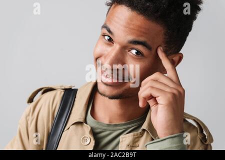 Immagine della lieta african american guy nel rivestire sorridente e toccando il suo tempio isolate su sfondo bianco Foto Stock