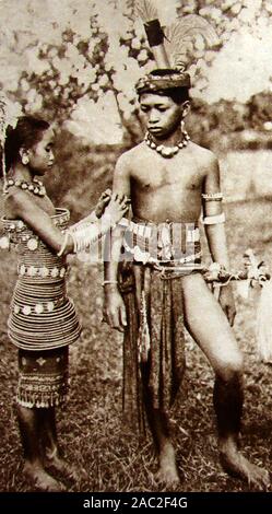 1930 vintage fotografia di due bambini dal Dyak (aka Dayuh) tribù native persone del Borneo (Iban o mare Dajak un ragazzo e una ragazza in abito tradizionale) Foto Stock