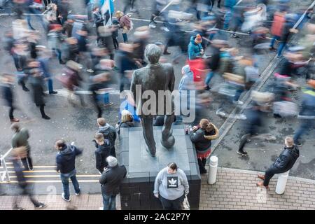 Newcastle, Inghilterra, Regno Unito. 30 Novembre, 2019. Sostenitori a piedi passato una statua di ex manager, Sir Bobby Robson, come flusso in St James Park in anticipo del mezzogiorno premier league tra Newcastle United e il Manchester City. Credito: Alan Dawson /Alamy Live News Foto Stock