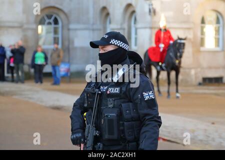 Un agente di polizia armato la protezione di cavalleria della famiglia durante il cambio della guardia a Whitehall, London, Regno Unito Foto Stock