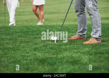 Immagine ritagliata del golfista che prendano di mira per il tiro. Due amici in piedi a sfondo Foto Stock