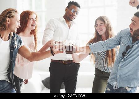 Diamo un drink. Cinque multirazziale lavoratori ufficio celebrano il loro successo nel business Foto Stock
