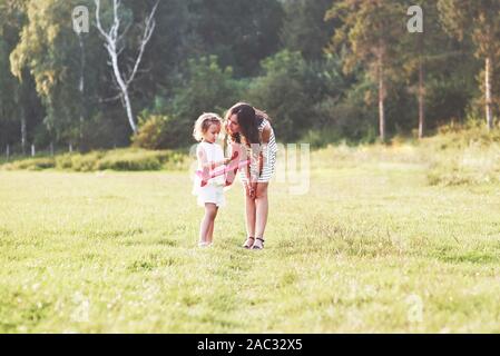 Bambino parlando di aeroplano giocattolo nelle mani di una madre all'aperto Foto Stock