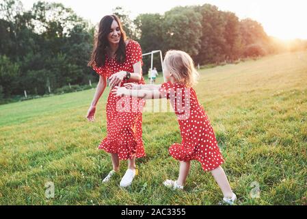 Catch me se è possibile. Giovane madre con sua figlia di trascorrere del tempo al di fuori in questo bellissimo luogo Foto Stock