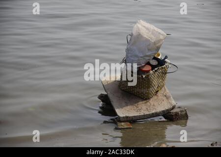 Dhobighat, il luogo in cui i vestiti sono lavati nel fiume Gange a Varanasi. Un cesto pieno di detersivo in polvere e altre cose sulla pietra di lavaggio Foto Stock