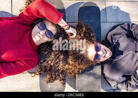 Due giovani skaters in appoggio con i capi sulle proprie schede Foto Stock