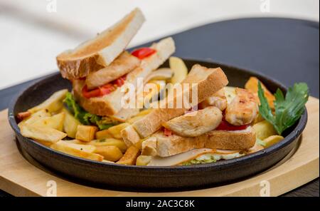 Sandwich di Pollo nel pane tostato, con le patatine fritte in un recipiente su uno sfondo bianco, ristorante, servita Foto Stock