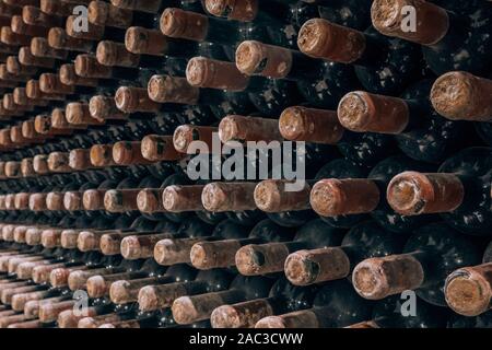 Le bottiglie di vino impilati nella vecchia cantina close-up sullo sfondo Foto Stock