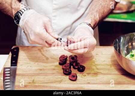 Lo chef è la rimozione delle pietre di ciliegia in cucina professionale, tonica immagine Foto Stock