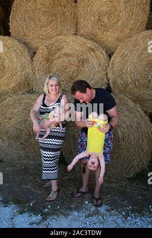 Ritratto di famiglia inglese in vacanza nella campagna francese, seduti su balle di paglia. Foto Stock