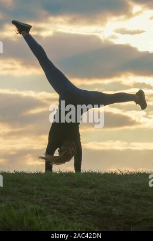 Giovane donna facendo appoggiate sull'erba mattina allenamento bellissima alba Foto Stock