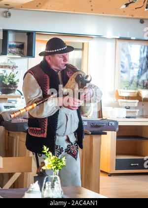 Tatry, Polonia - Giugno 03, 2019: etnico highlander (Góral) nei tradizionali goral abito con cappello nero gioca su cornamuse. Monti Tatra. Gora Foto Stock