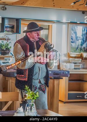 Tatry, Polonia - Giugno 03, 2019: etnico highlander (Góral) nei tradizionali goral abito con cappello nero gioca su cornamuse. Monti Tatra. Gora Foto Stock