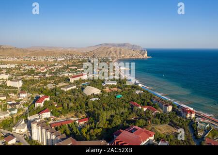 La cittadina di Sudak in Crimea da una vista di altezza della linea costiera con spiagge e le montagne in distanza Foto Stock