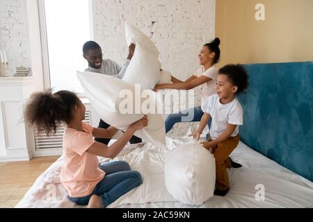 Overjoyed americano africano famiglia con bambini a giocare in camera da letto Foto Stock