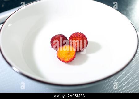 Il corbezzolo albero: due frutti maturi nel piattino e tagliata a fette Foto Stock