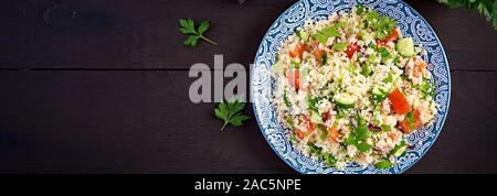 Tradizionale insalata libanese tabulé. Il couscous con il prezzemolo, pomodoro, cetriolo, limone e olio di oliva. Cucina medio-orientale. Vista superiore, banner Foto Stock