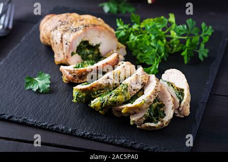 Arrosto di Natale a fette il rotolo di tacchino con spinaci e formaggio rustico scuro dello sfondo. Festival del cibo. Foto Stock