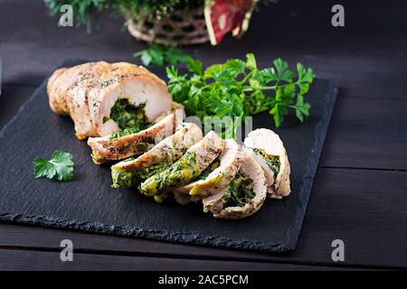 Arrosto di Natale a fette il rotolo di tacchino con spinaci e formaggio rustico scuro dello sfondo. Festival del cibo. Foto Stock