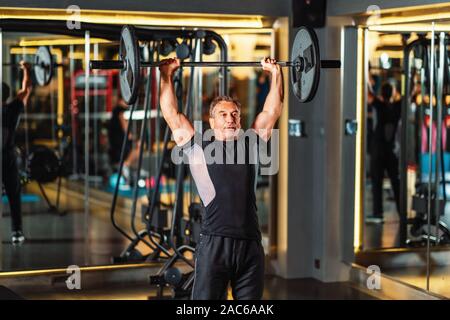 L'uomo rafforza i muscoli addominali e i muscoli del braccio in palestra Foto Stock