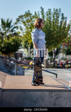 Ragazza adolescente corse su uno skateboard. Bellissimo quartiere alla moda di guidatore di skateboard in jeans e una felpa con cappuccio sulla rampa. Foto Stock