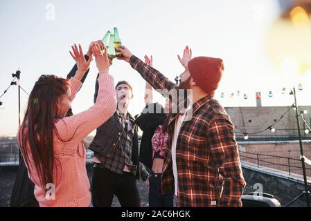 Vacanze sul tetto. Allegro gruppo di amici ha sollevato le mani con alcool Foto Stock