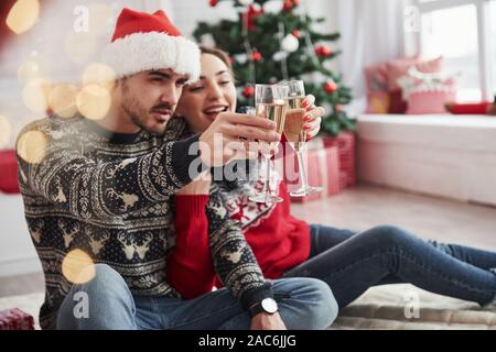 Fare un brindisi. Due persone si siede sul pavimento e festeggiare il nuovo anno Foto Stock