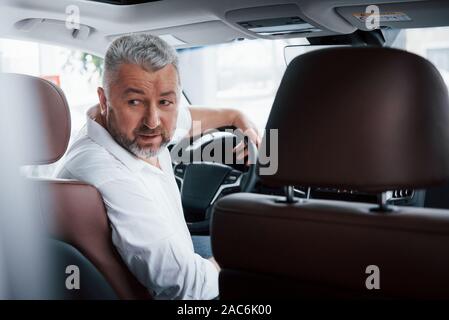 Alla guida di una vettura in retromarcia. Guardando dietro. L uomo nella sua nuovissima automobile Foto Stock