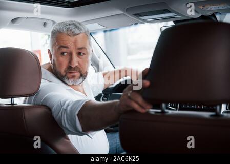 La prova del veicolo. Alla guida di una vettura in retromarcia. Guardando dietro. L uomo nella sua nuovissima automobile Foto Stock