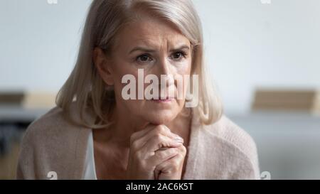 Malinconici donna matura si sente sollecitata perso in pensieri seduta in ambienti interni Foto Stock