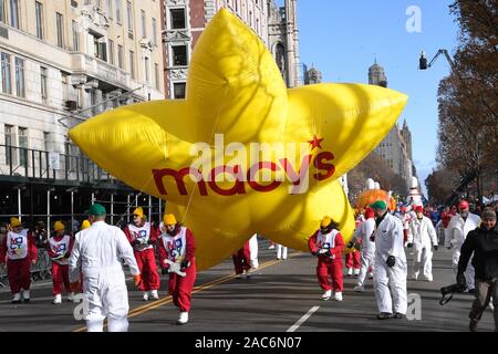 NEW YORK, NY - novembre 28: gestori di eventi di lotta per mantenere il giallo Macy's star palloncino bassa a causa del vento forte alla 93ma Macy annuale per il giorno del Ringraziamento parata del Novembre 28, 2019 a New York City. Foto Stock