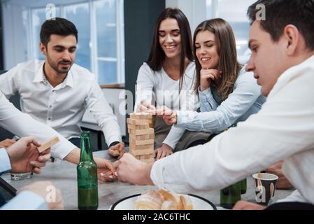 Giocare intorno. Per celebrare il successo della trattativa. I giovani lavoratori ufficio seduta vicino alla tabella con alcol Foto Stock