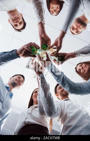 Foto verticale. Vista dal basso. Occhiali di detonazione in ufficio. Per celebrare il successo Foto Stock