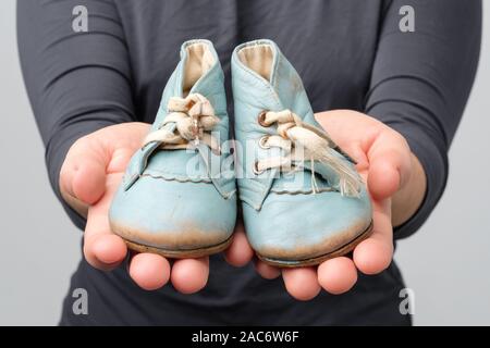 Donna che mantiene il vecchio retrò scarpe per bambini. Vista ravvicinata Foto Stock